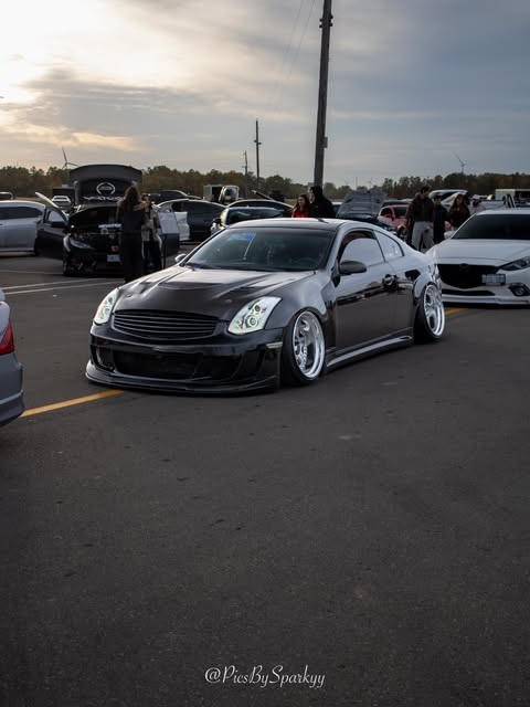 Low black Infiniti coupe with polished wheels at a car meet, photographed by Connor